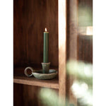 Green candle in a rustic ceramic holder