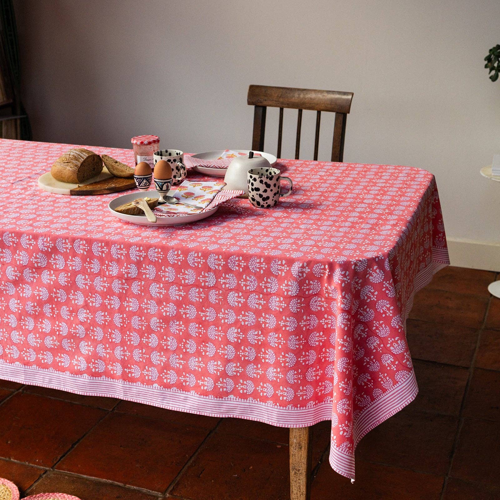 Dining table styled with a vibrant coral print tablecloth by Constance and Denny