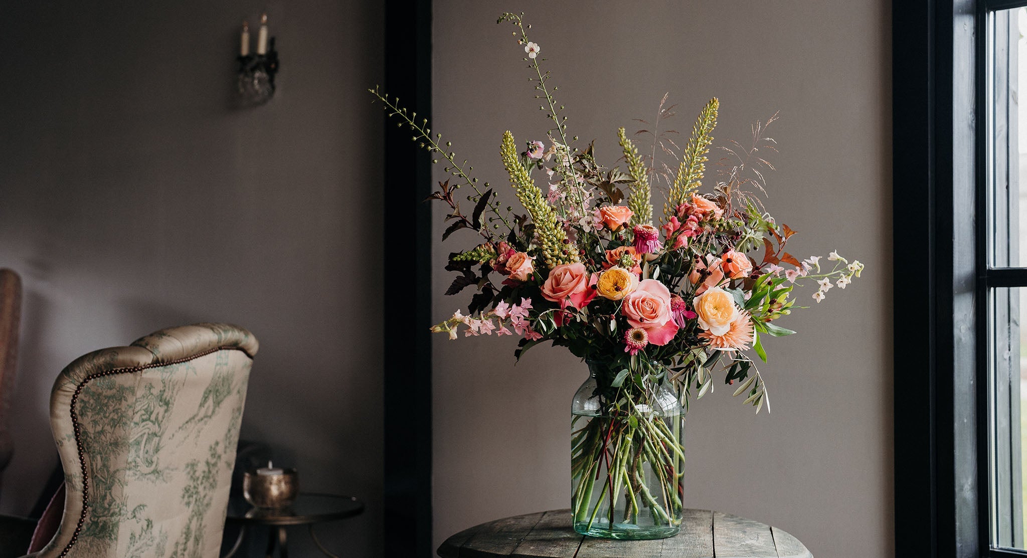 Luxury bouquet featuring Coral Charm peonies, viburnum, snapdragons, lisianthus, stocks and olive foliage arranged in a wild, romantic garden style by Mad Lilies.