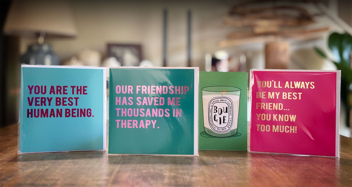 Four friendship cards with different sayings on a wooden surface.