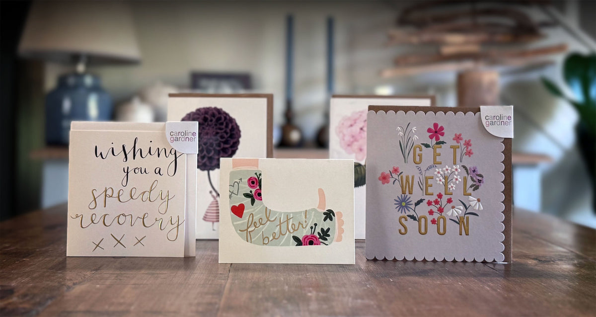 Collection of get well soon cards on a wooden surface with a blurred indoor background.