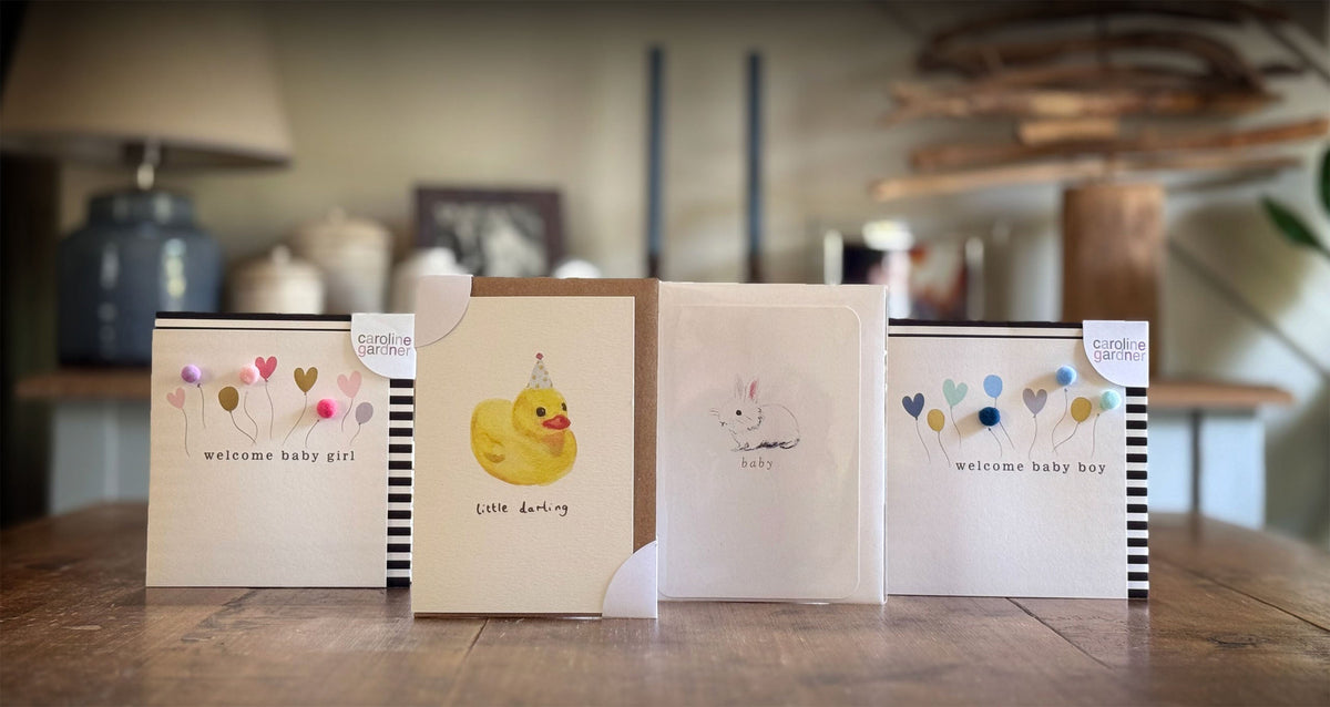 Set of baby shower cards on a wooden surface with a blurred indoor background