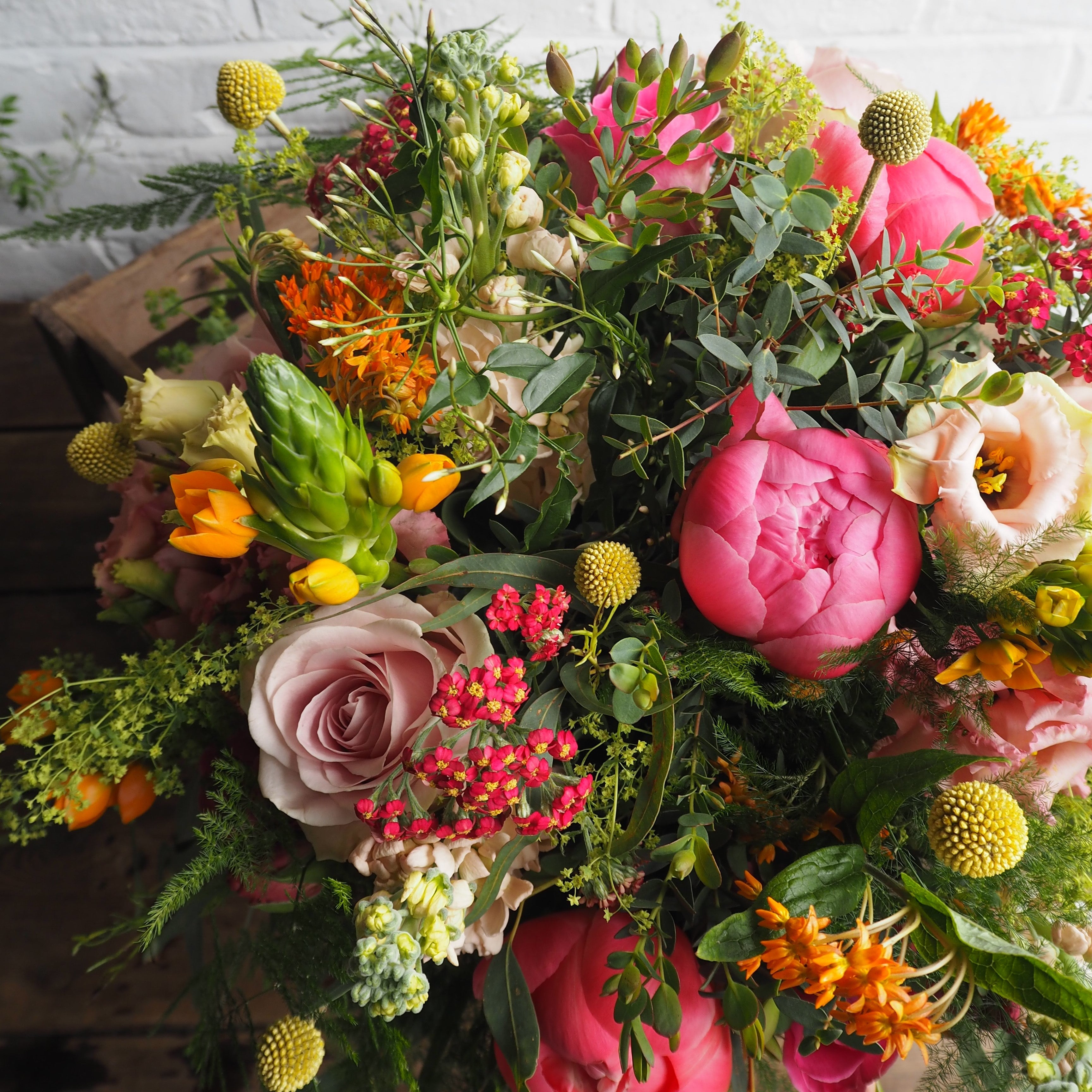 Luxury bouquet featuring Coral Charm peonies, viburnum, snapdragons, lisianthus, stocks and olive foliage arranged in a wild, romantic garden style by Mad Lilies.