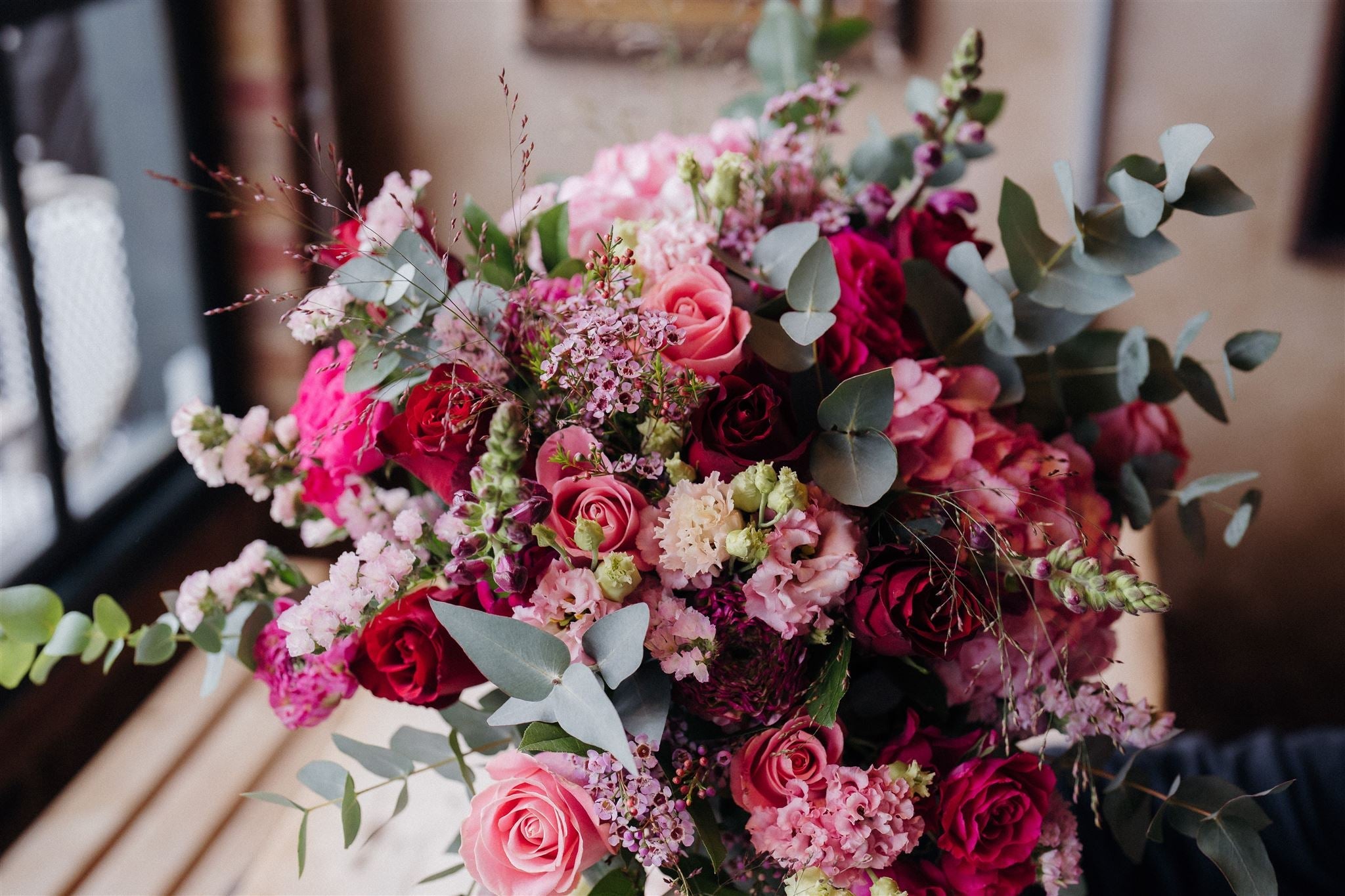 Luxury bouquet featuring Coral Charm peonies, viburnum, snapdragons, lisianthus, stocks and olive foliage arranged in a wild, romantic garden style by Mad Lilies.