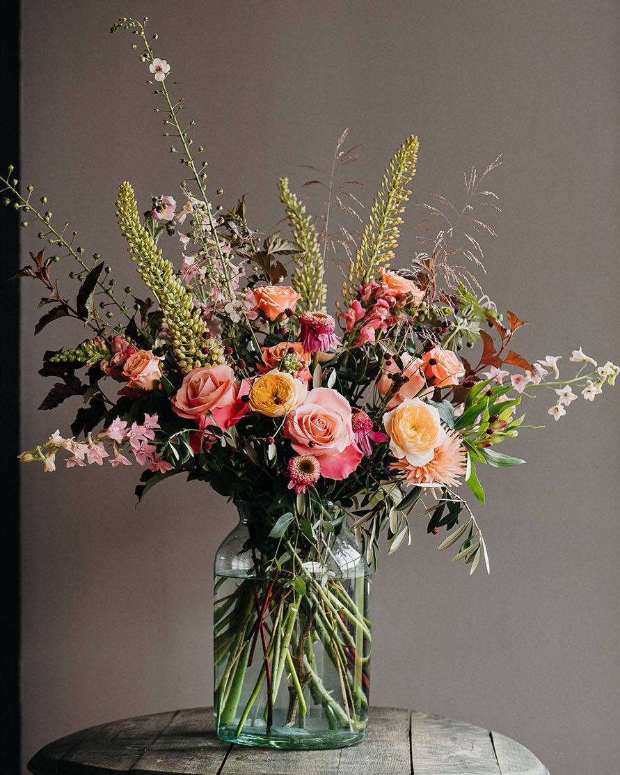 Luxury bouquet featuring Coral Charm peonies, viburnum, snapdragons, lisianthus, stocks and olive foliage arranged in a wild, romantic garden style by Mad Lilies.