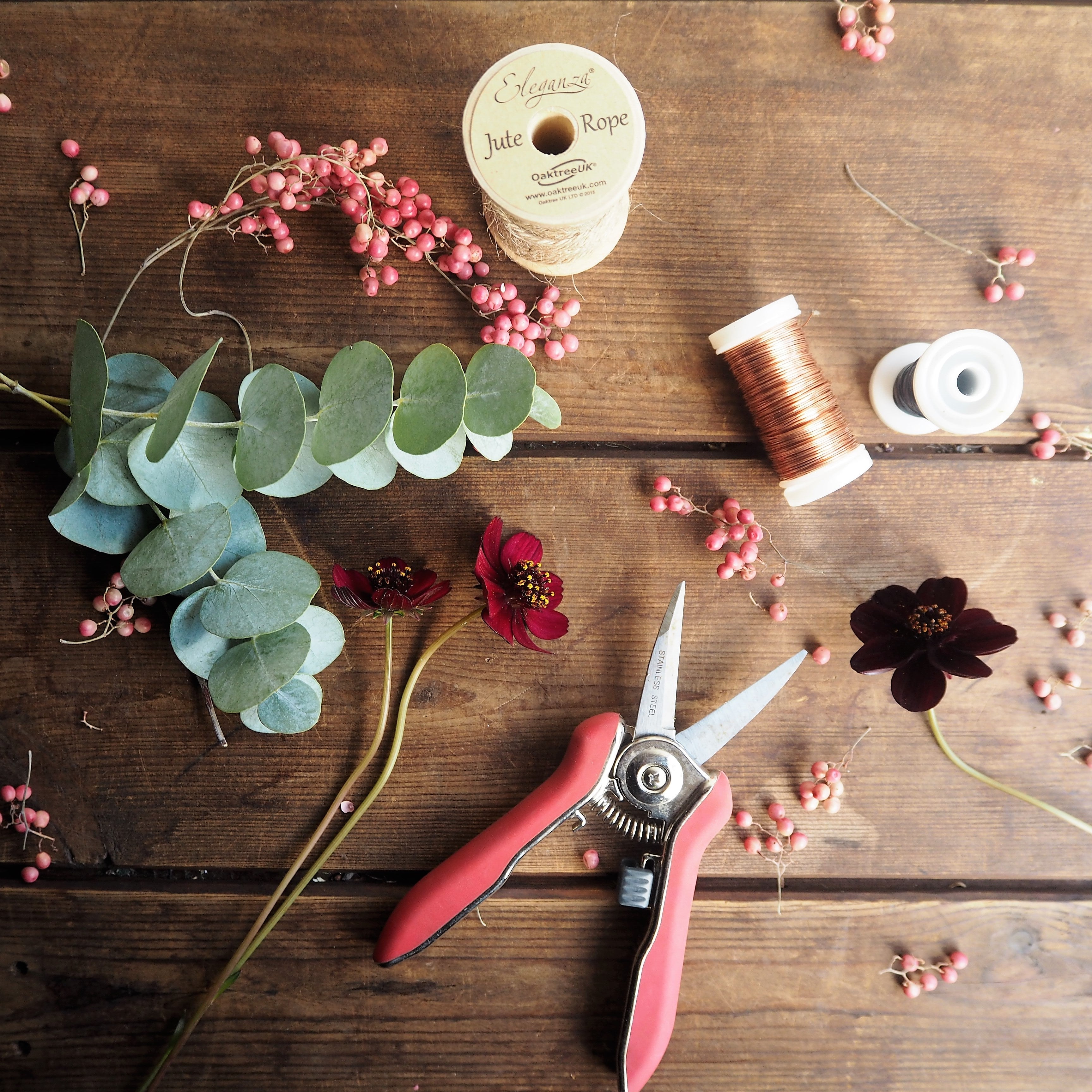 Floristry scissors, floral wire and fresh flower stems on a wooden table