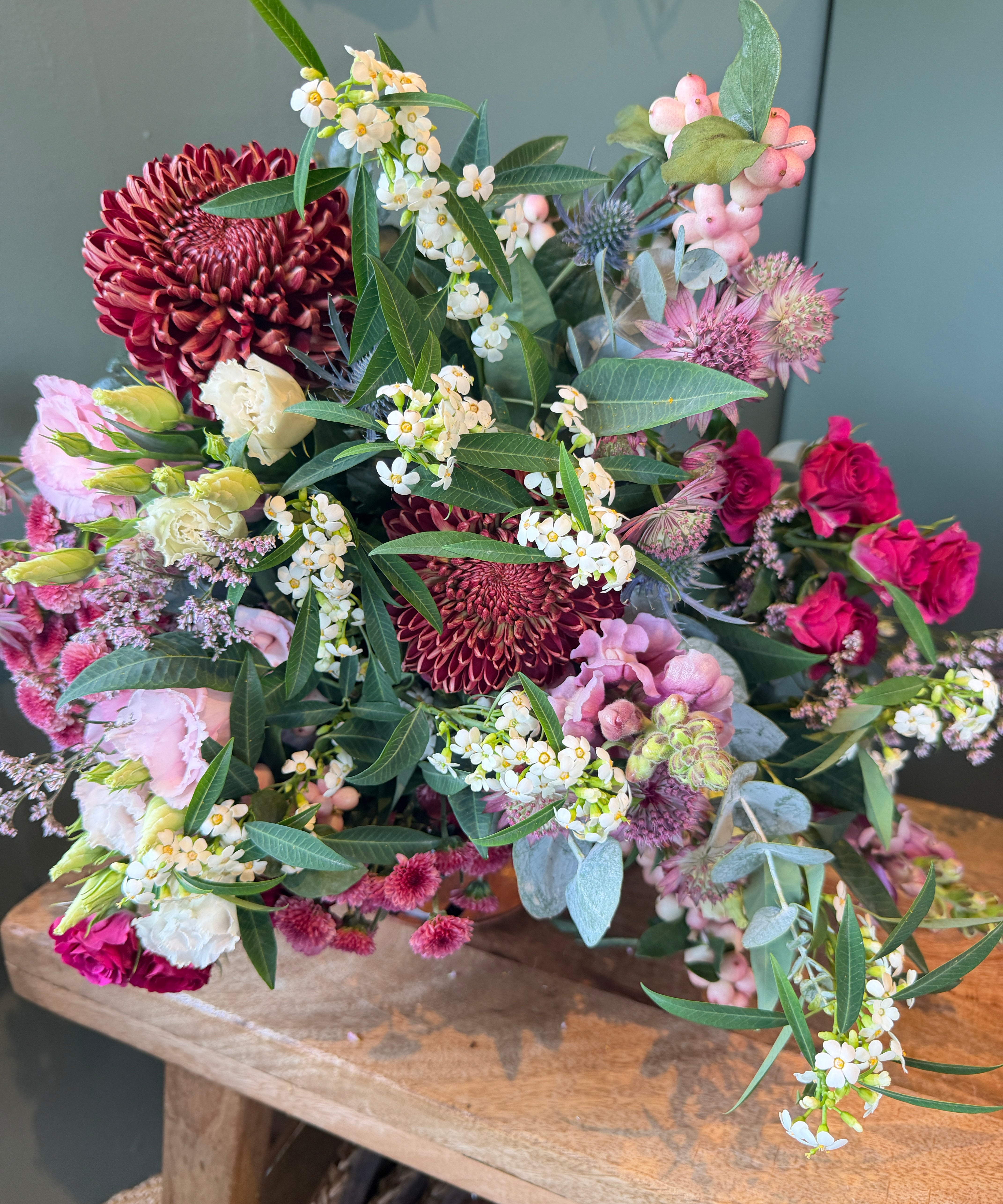 October Bouquet of the Month with burgundy flowers, hot pink roses, snowberry, eryngium and eucalyptus