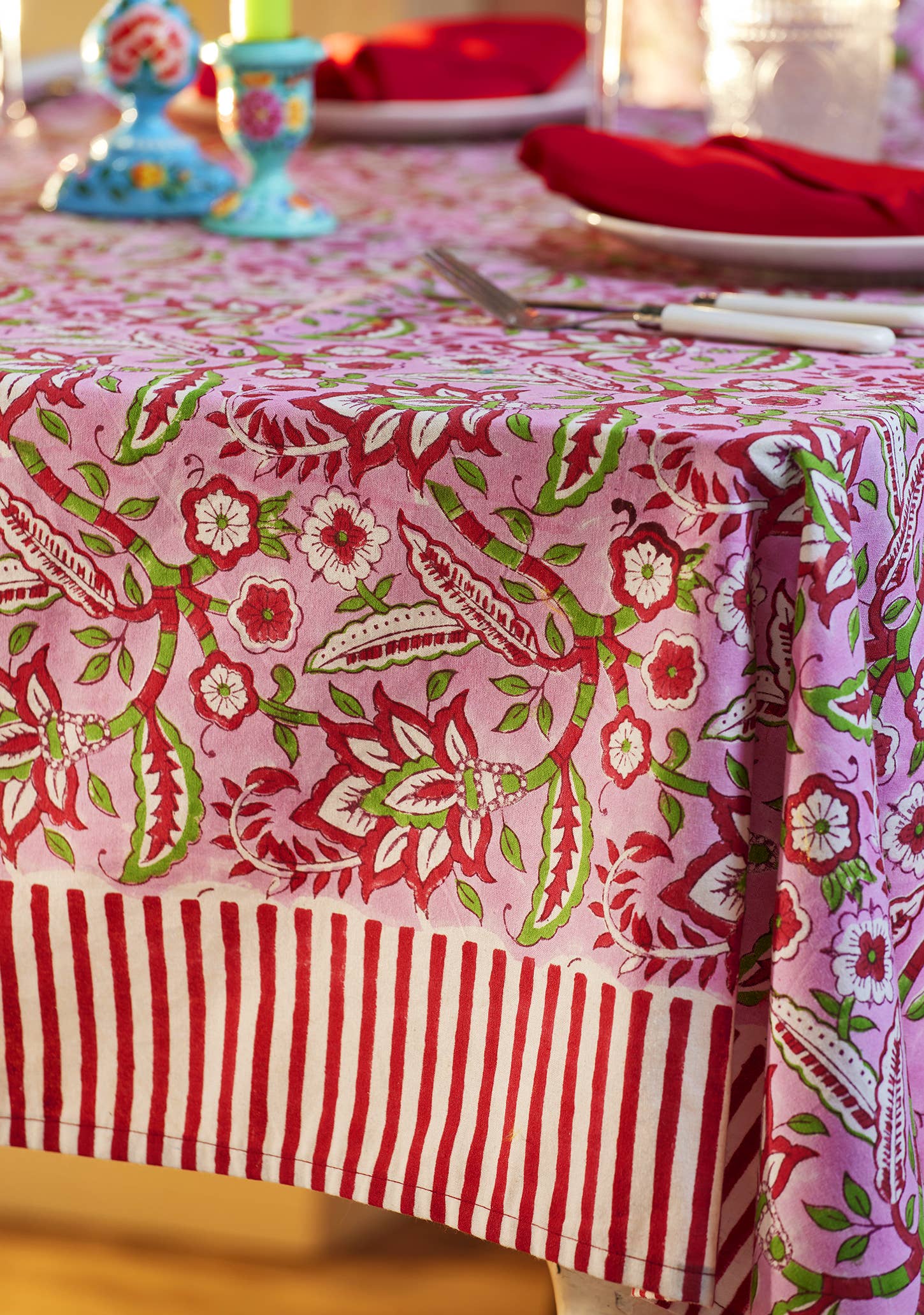 Pink floral block print cotton tablecloth with red and white candy stripe border styled for elegant dining and entertaining.