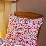 Pink floral block print cotton cushion cover with red striped reverse and decorative beaded edging styled on a sofa.