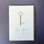 Penguin Ink New Home Key letterpress greeting card featuring a vintage key with metallic gold detailing and modern calligraphy, printed on 100% recycled board with a tactile embossed finish.