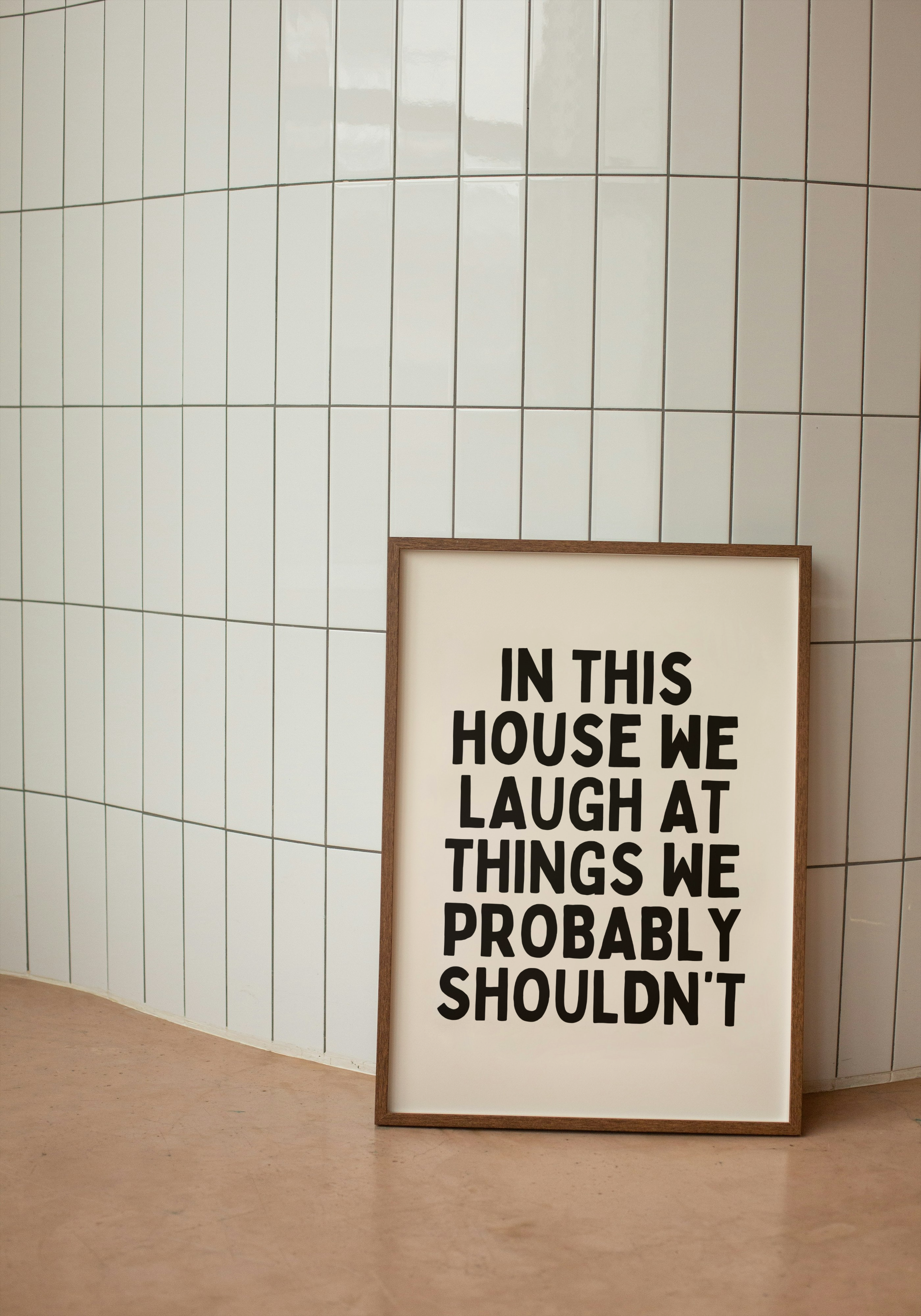 Framed poster with humorous text 'In this house we laugh at things we probably shouldn't' 