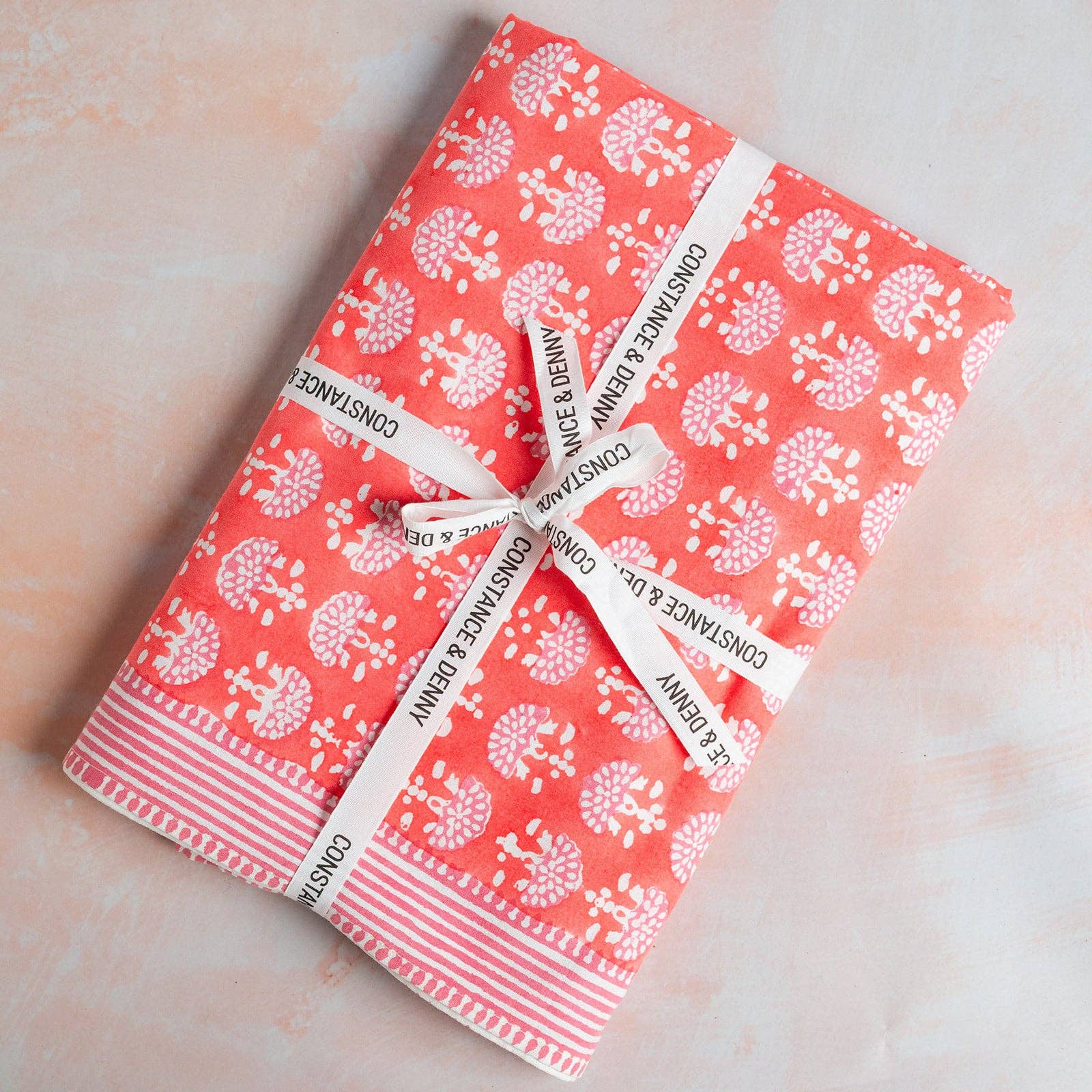 Coral hand block printed cotton tablecloth with pink fan motifs and striped border styled on an elegant dining table.