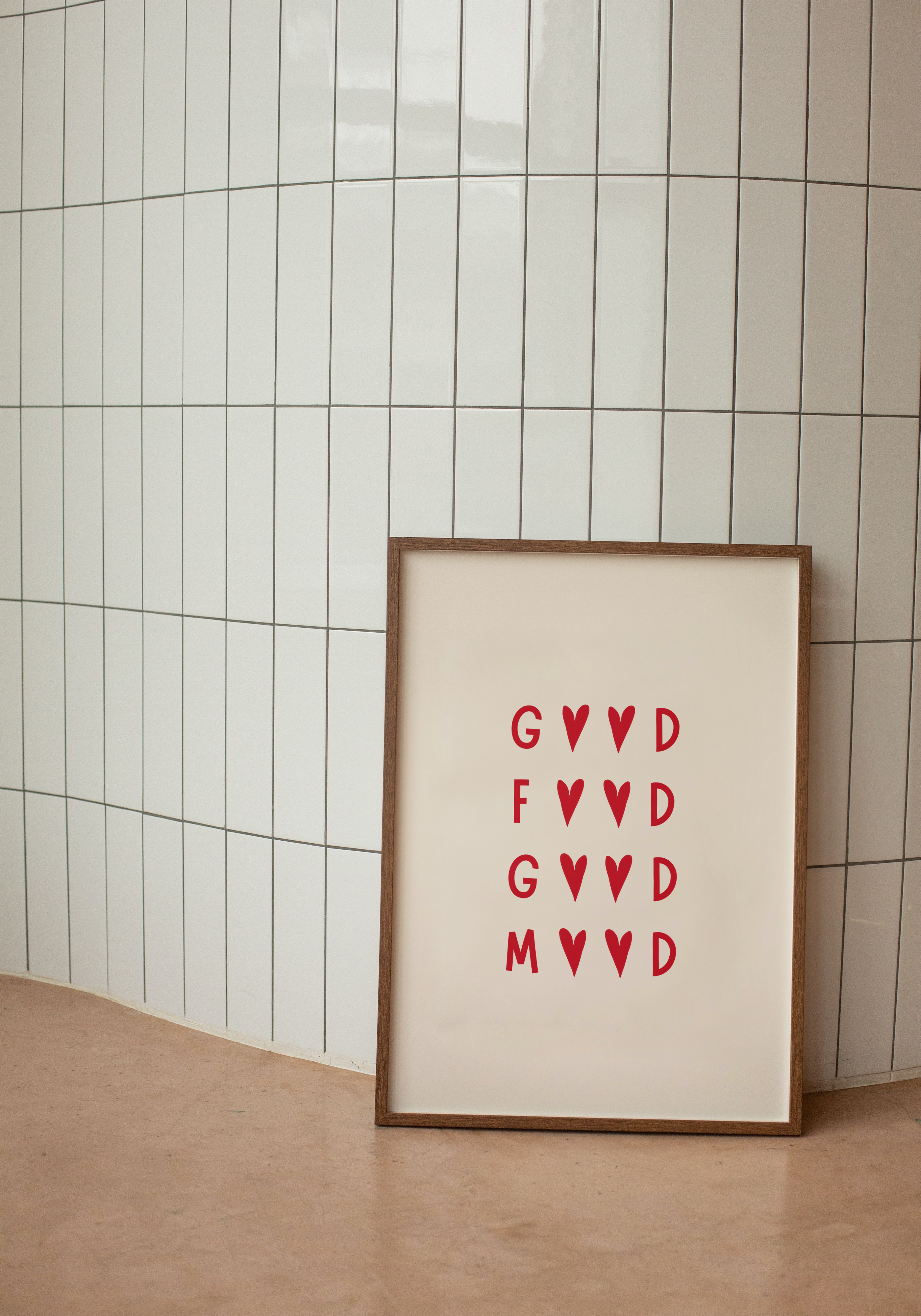 Framed artwork with red Good Food Good Mood text on a beige background against a tiled wall.