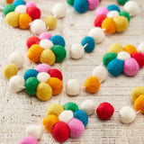 Colourful wool felt flower garland with felt ball details hanging as decorative reusable party and home décor.
