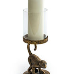 An antiqued bronze crouching monkey candle holder with a glass cover for a candle