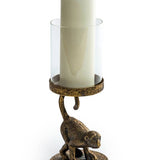 An antiqued bronze crouching monkey candle holder with a glass cover for a candle