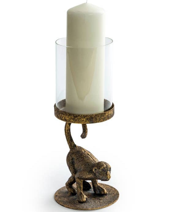 An antiqued bronze crouching monkey candle holder with a glass cover for a candle