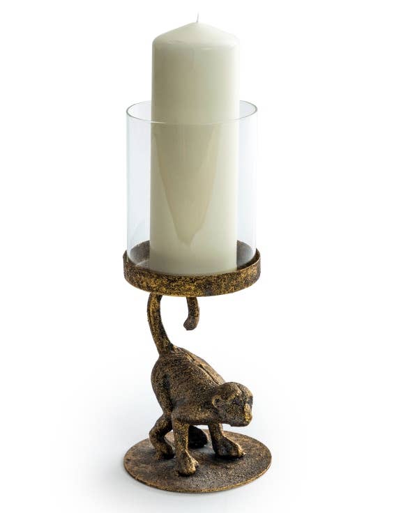 An antiqued bronze crouching monkey candle holder with a glass cover for a candle