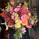 Bouquet of colorful flowers held by a person in a blurred indoor setting