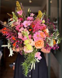 Bouquet of colorful flowers held by a person in a blurred indoor setting