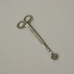 Stainless steel wick trimmer with a looped end and the True Grace emblem engraved on the handle