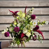 Bouquet of flowers with white, purple, and green colors against a wooden background
