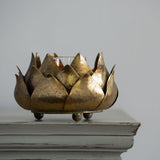 A gold-colored metal artichoke-shaped candle holder with a glass inser