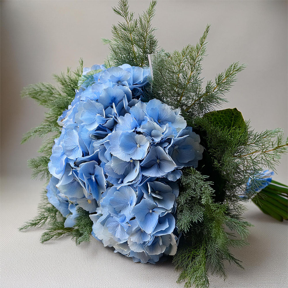 omething Blue Hydrangeas – luxury blue hydrangea stems with large cloud-like blooms arranged in a vase.