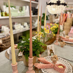 Decorative pink and yellow candles on a table with a blurred store interior in the background
