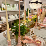 Decorative pink and yellow candles on a table with a blurred store interior in the background