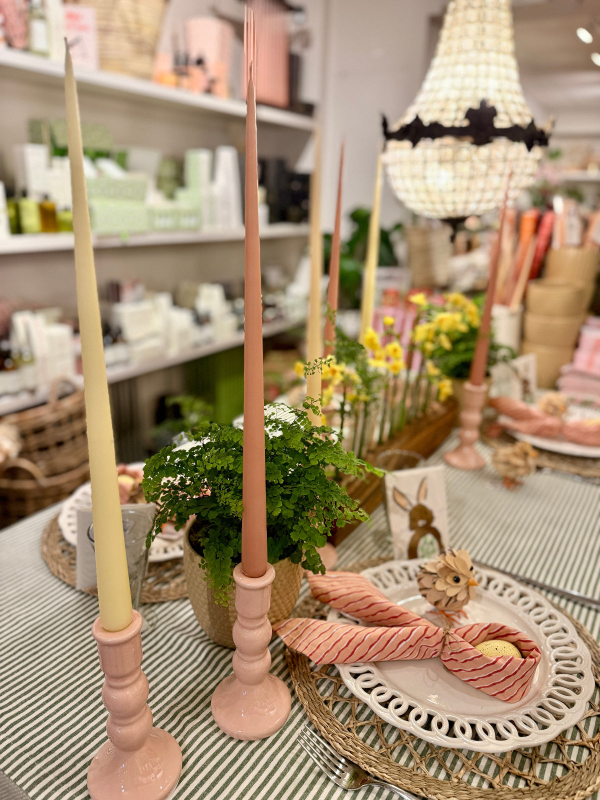 Decorative pink and yellow candles on a table with a blurred store interior in the background