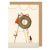 Illustrated greeting card with people decorating a Christmas wreath on a white background