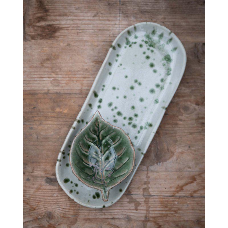 Ceramic tray with leaf design on a wooden surface