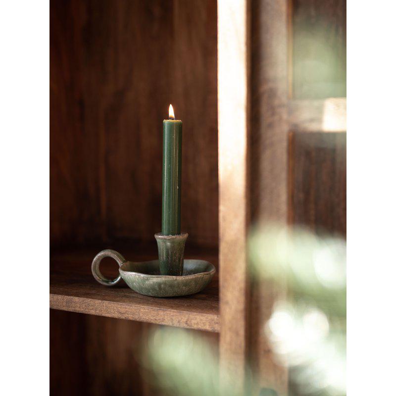 Green candle in a rustic ceramic holder 