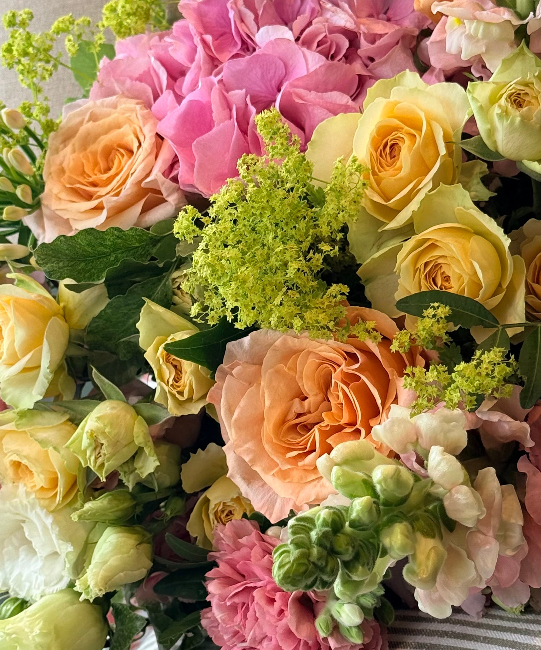 July Bouquet of the Month featuring pink hydrangeas, apricot roses, yellow Bandolero roses, snapdragons and seasonal summer flowers.