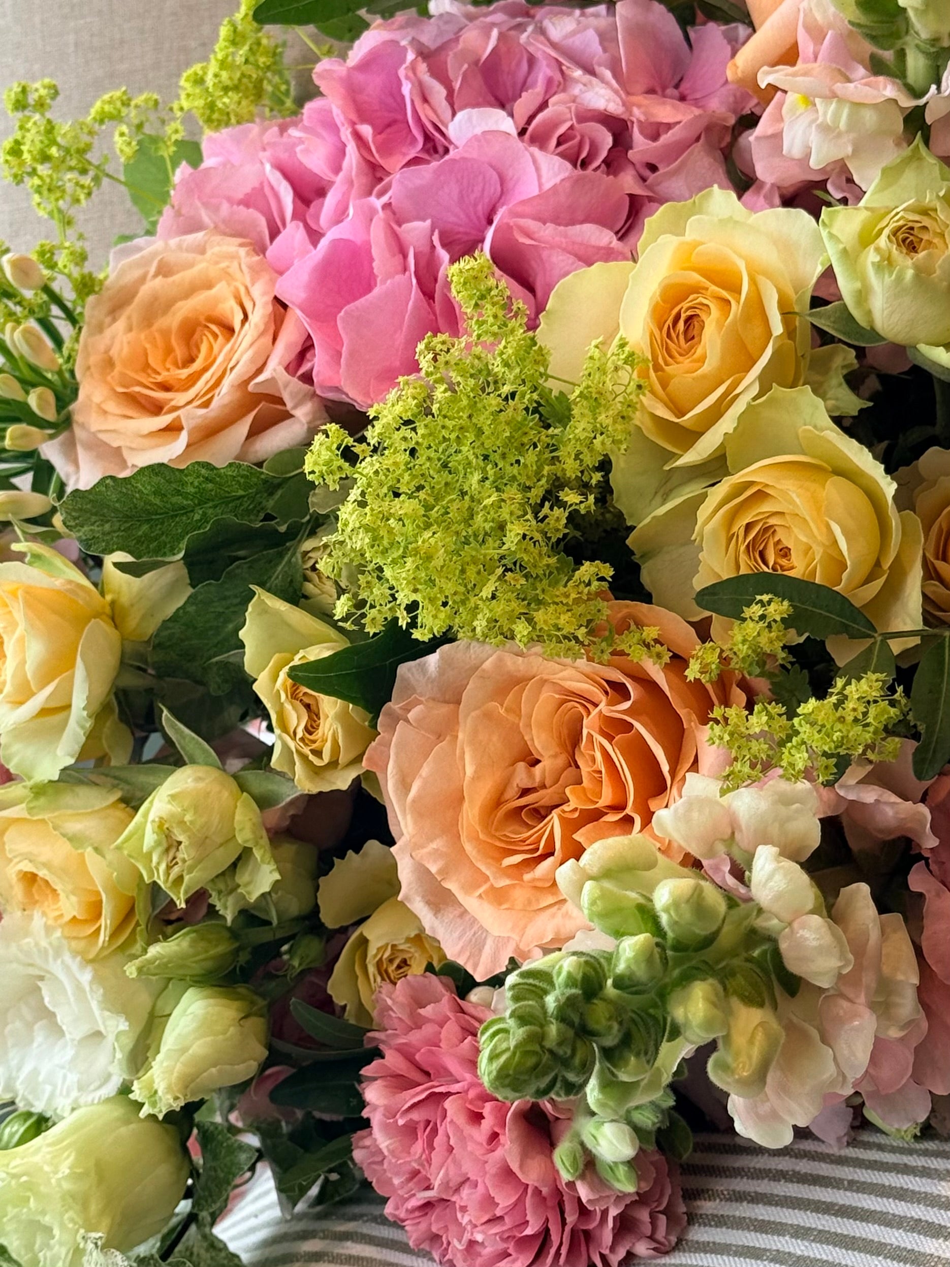 July Bouquet of the Month featuring pink hydrangeas, apricot roses, yellow Bandolero roses, snapdragons and seasonal summer flowers.