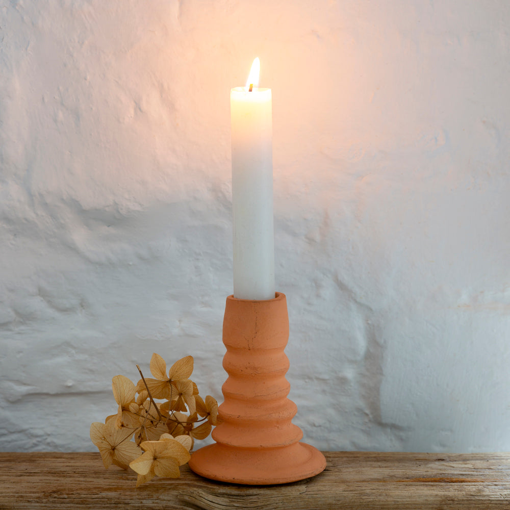 A terracotta candle holder with a conical shape