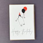 Penguin Ink Happy Birthday Penguin letterpress card featuring a chinstrap penguin wearing a neon spotty party hat and holding balloons, printed on 100% recycled board with an embossed finish.