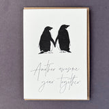Penguin Ink Another Awesome Year Together letterpress card featuring two gentoo penguins touching flippers, printed on 100% recycled board with a tactile embossed finish.