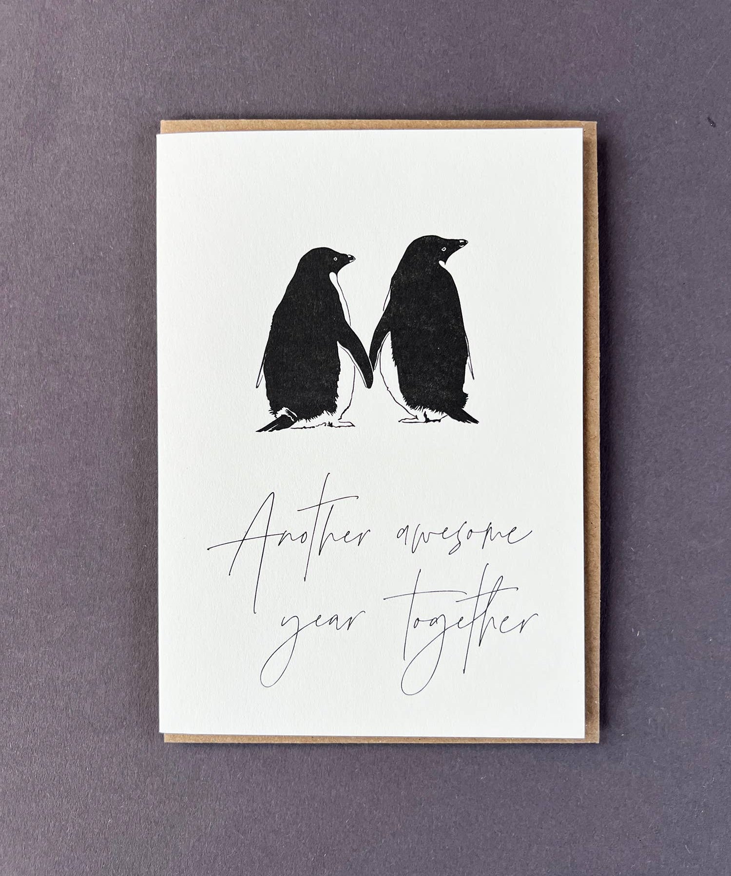 Penguin Ink Another Awesome Year Together letterpress card featuring two gentoo penguins touching flippers, printed on 100% recycled board with a tactile embossed finish.