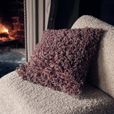 Abigail Ahern Harlem textured cushion with a soft shaggy finish in a neutral colourway, styled on a sofa for a warm, layered interior.