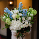A luxury Blue Sky bouquet with white hydrangeas, blue delphiniums and seasonal flowers. Hand-tied by Mad Lilies with local Surrey and UK delivery.