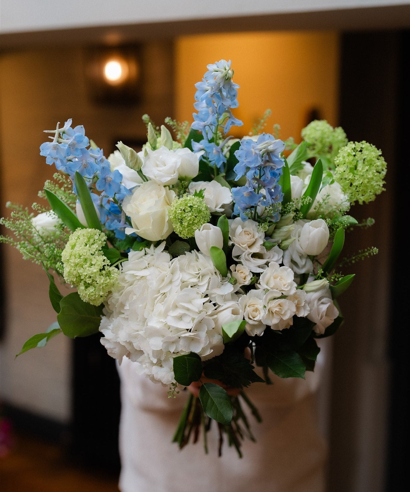 A luxury Blue Sky bouquet with white hydrangeas, blue delphiniums and seasonal flowers. Hand-tied by Mad Lilies with local Surrey and UK delivery.