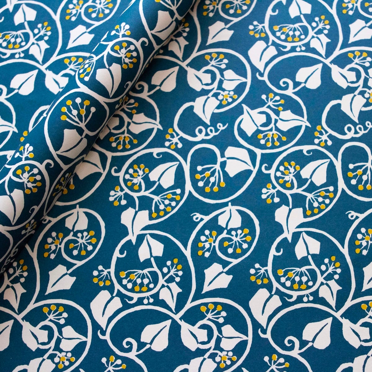 Cambridge Imprint Ivy wrapping paper in deep marine blue and acid yellow, featuring flowing ivy tendrils and contrasting berries.