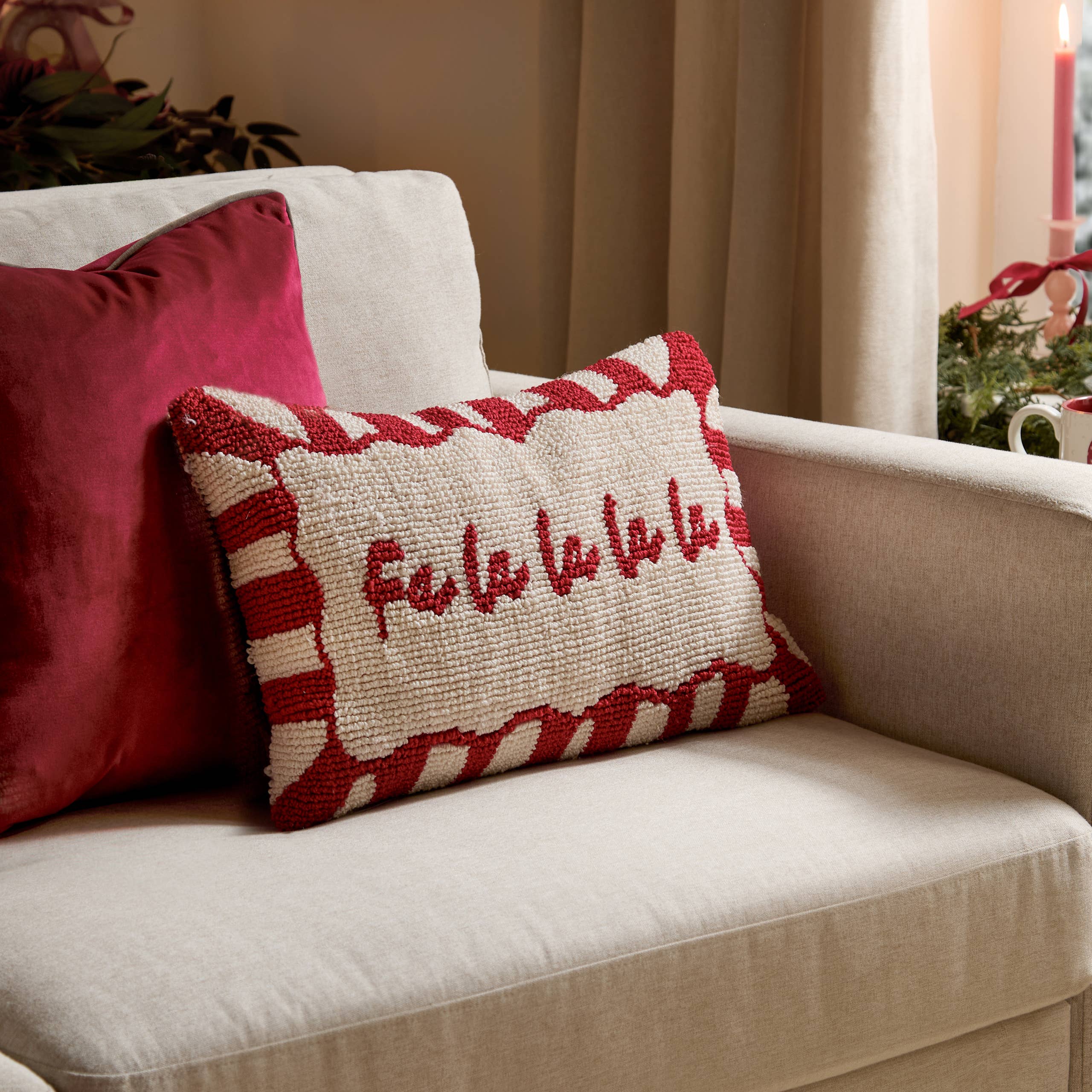 Candy Fa La La Christmas cushion with colourful candy stripes and tufted festive lettering