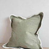 Chloe sage scalloped cushion in soft green with decorative scalloped edging, styled on a sofa in a modern country living room.