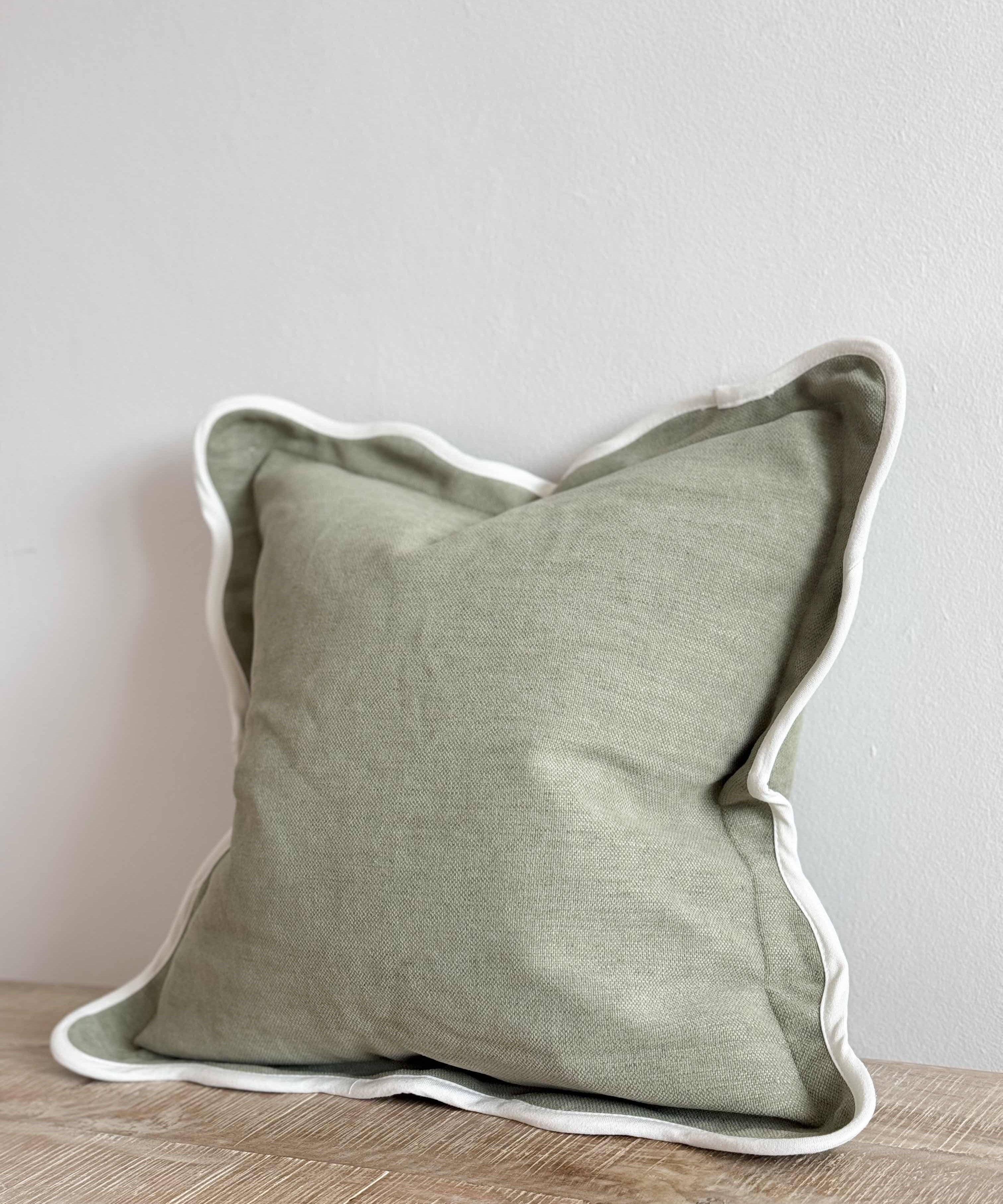 Chloe sage scalloped cushion in soft green with decorative scalloped edging, styled on a sofa in a modern country living room.