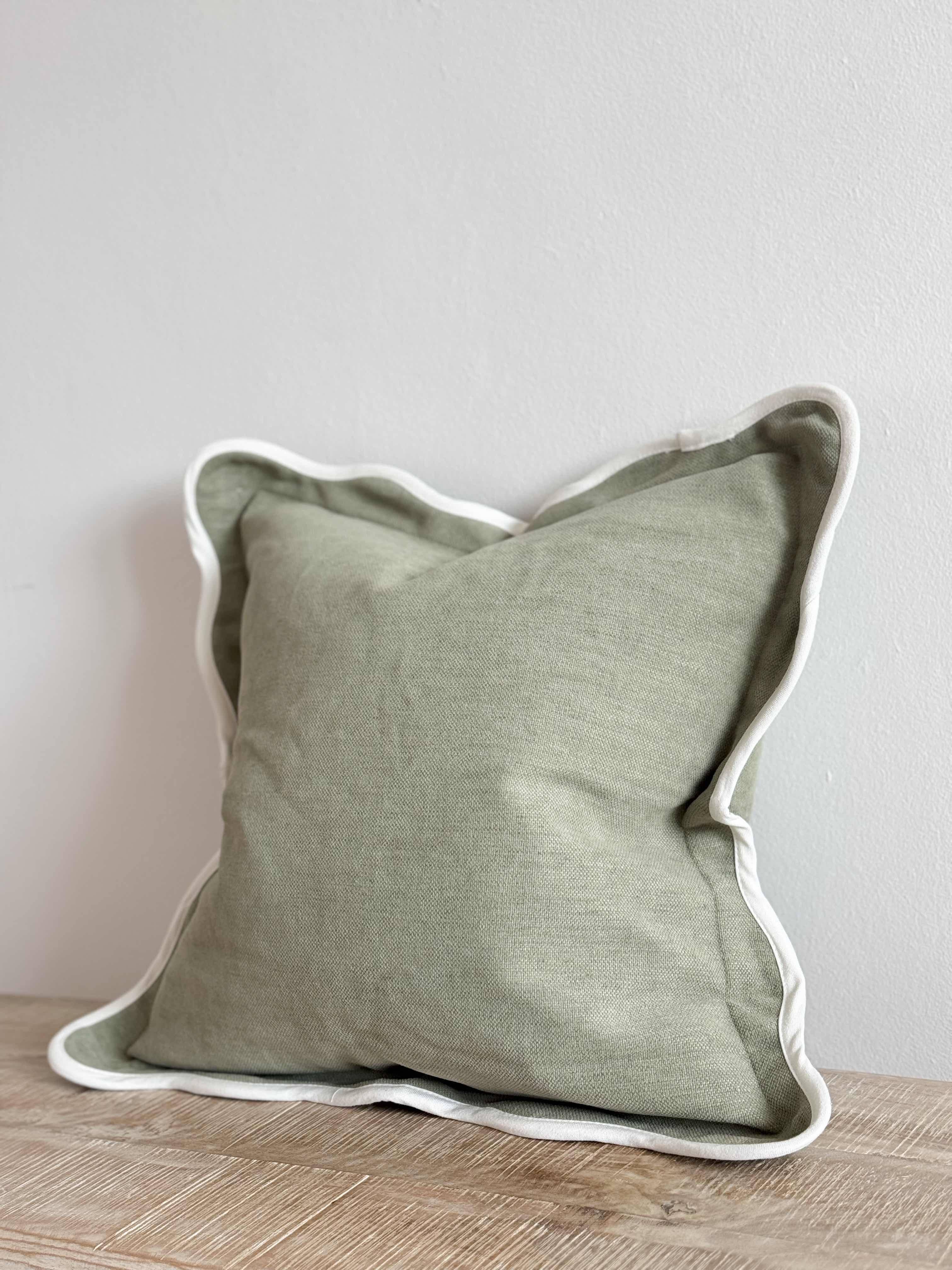 Chloe sage scalloped cushion in soft green with decorative scalloped edging, styled on a sofa in a modern country living room.