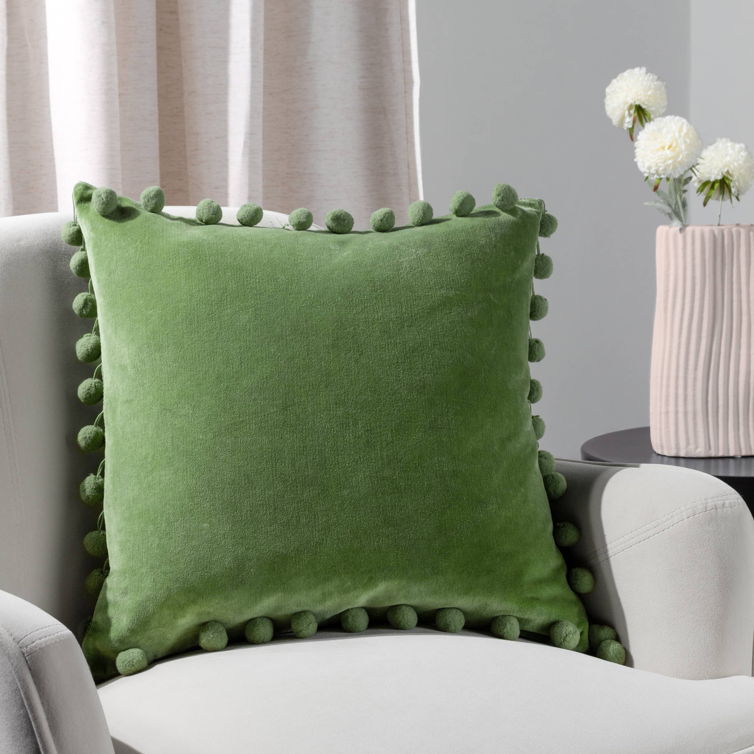 Leaf green cotton velvet cushion with playful pom-pom trim and hidden zip. 100% cotton fabric, machine washable and available with feather or polyester filling.