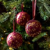Berry red and gold papier-mâché Christmas baubles with hand-painted sprigs and velvet ribbons